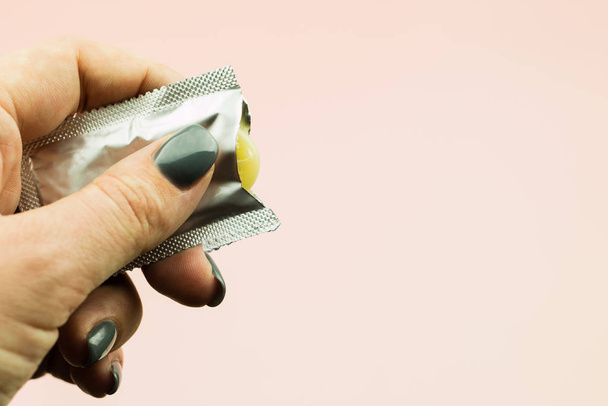 Main de femme tenant le préservatif ouvert en paquet
 - Photo, image