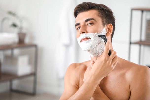 Красивий молодий чоловік голиться вдома
 - Фото, зображення