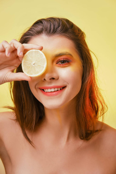 Portrait of a smiling girl with bright makeup on a yellow background.  - Foto, Imagen