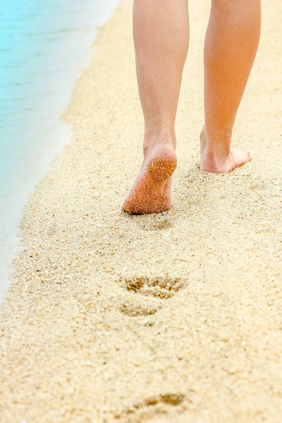 gyönyörű lábnyomok a homokban a tenger háttere mellett - Fotó, kép