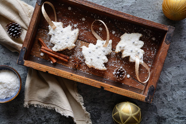 バニラクリームと細切りココナッツの上にクリスマスツリークッキーをカット - 写真・画像