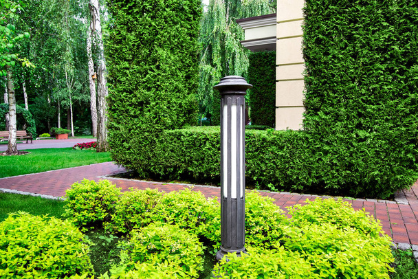 a garden ground lamp in the green bushes and pedestrian walkway on park. - Φωτογραφία, εικόνα
