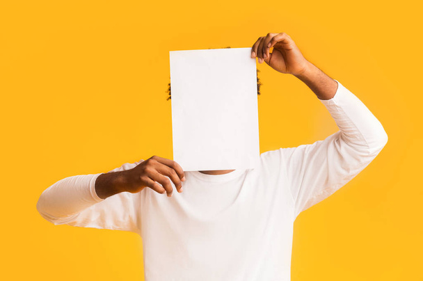 Man covering his face with empty white paper - 写真・画像