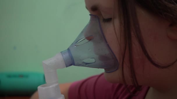 Tienermeisje ademt een zuurstofmasker in. Inademing van de luchtwegen. Masker inhalator. - Video