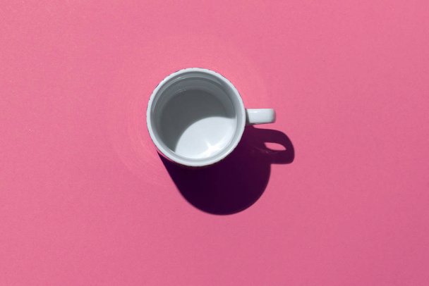 Empty tea cup on pink paper background. Coffee mug from above. Minimal concept Hard deep shadow. Flat lay, top view. - Photo, Image