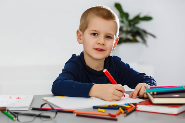 Розумний, веселий, щасливий, маленький хлопчик, школяр за столом вирішує проблеми та уроки
   - Фото, зображення
