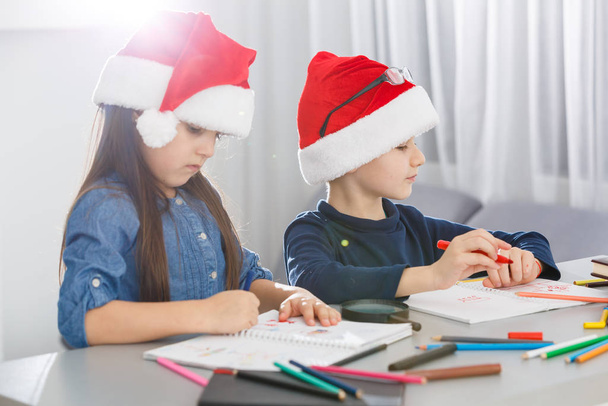 fröhliche kleine Kinder in Weihnachtsmützen auf weißem Hintergrund. Weihnachtsfeier  - Foto, Bild