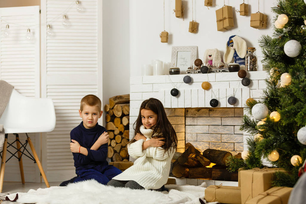 Család karácsony este a kandallóban. Gyerekek a karácsonyfa alatt ajándékdobozokkal. Díszített nappali hagyományos kandallóval. Hangulatos meleg téli este otthon.  - Fotó, kép
