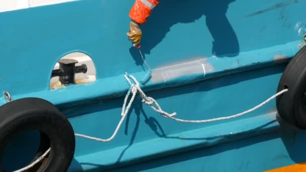 Ręka marynarza malującego farbą z rolkową rufą statku lub łodzią z niebieską farbą - Materiał filmowy, wideo