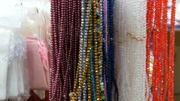 Wielokolorowe koraliki z różnych kamieni naturalnych wiszą w sklepie jubilerskim w Stambule. Kolorowe koraliki naszyjniki modne kobiece oświadczenie biżuteria, Kobieta ręka wybierze koraliki - Materiał filmowy, wideo