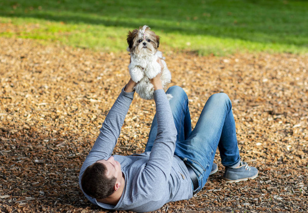 homem andando em um parque em cones com um filhote de cachorro bonito interagindo com um animal - Foto, Imagem