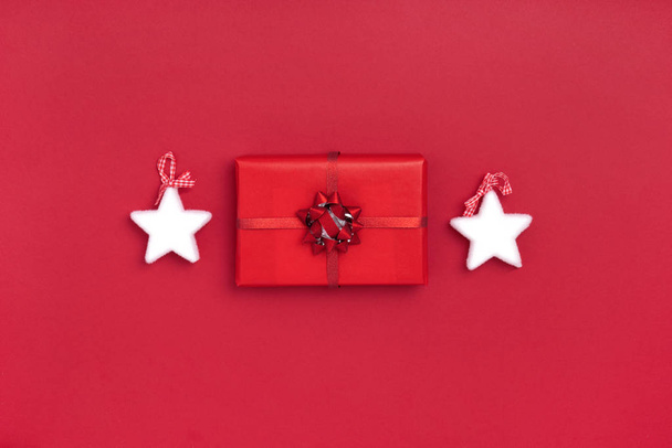 New Year and Christmas composition from white stars, gift box on red background. Top view, flat lay, copy space - Photo, Image