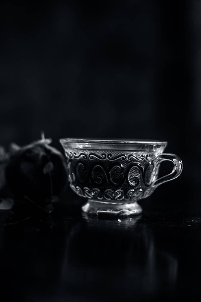 Best detoxify drink on a black glossy surface in a glass cup. Beetroot tea in a transparent glass cup on a black surface with a raw beet and some mint leaves. Vertical shot with blurred background. - Zdjęcie, obraz