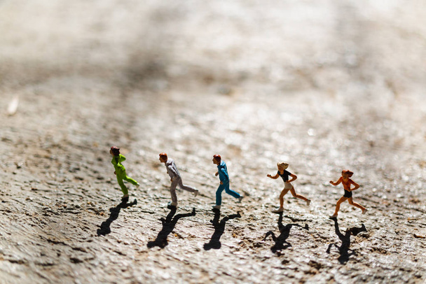Miniaturowi ludzie: Grupa ludzi biegnie po betonowej podłodze - Zdjęcie, obraz
