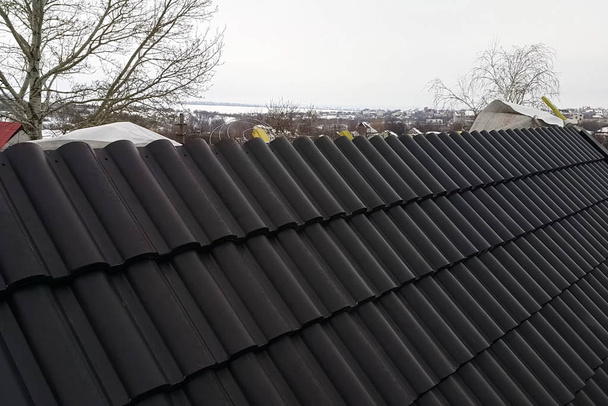 Installation du toit de la maison à partir de carreaux de céramique noire
. - Photo, image