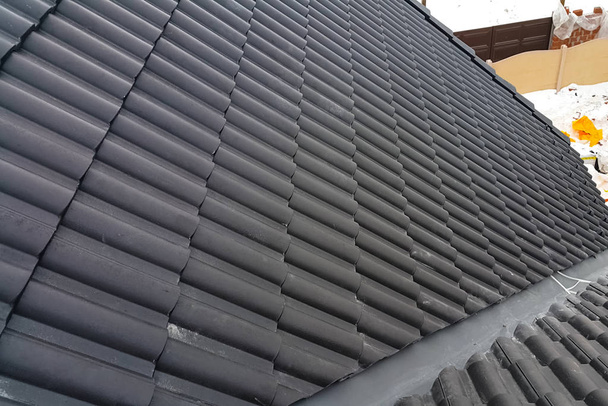Instalación del techo de la casa a partir de baldosas negras de cerámica
. - Foto, Imagen