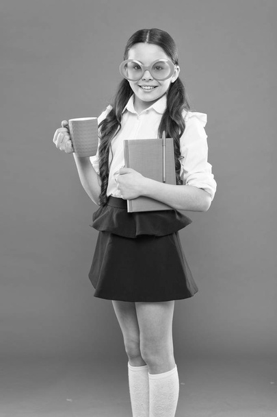 lunch time. happy school girl in uniform and party glasses. small child with notebook. reading education. writing in workbook. children literature. get information from book. kid reporter drink tea - Photo, image
