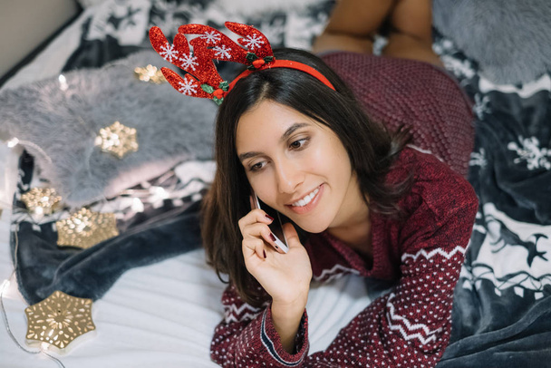 Girl with deer headband talking on phone in the bedroom - 写真・画像