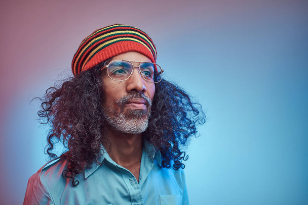Studio portret van Afrikaanse Rastafari man met een blauw shirt en beanie. - Foto, afbeelding
