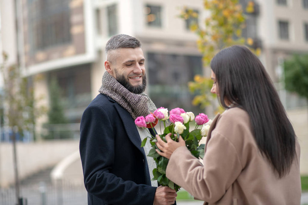 Positive dark haired woman taking a beautiful bouquet - Photo, image