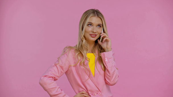 glimlachende vrouw praten in smartphone geïsoleerd op roze - Video