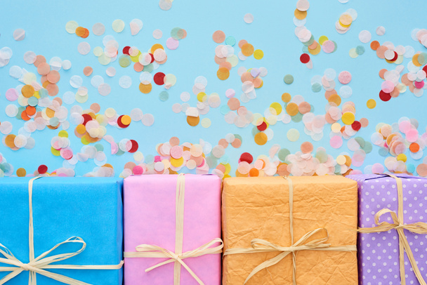 vue de dessus des boîtes-cadeaux colorées et enveloppées près de confettis sur bleu
  - Photo, image