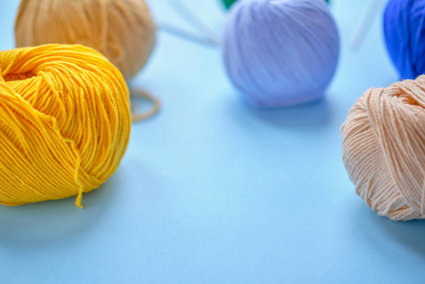 Heldere kleur garen spleten op de blauwe achtergrond. Concept van amigurumi speelgoed maken, handwerk, breien, hobbie - Foto, afbeelding