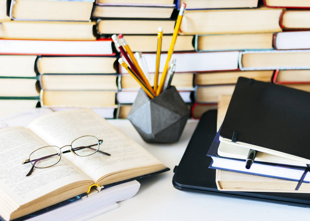 Stack of books, notebook, laptop, glasses in office background f - Foto, Bild