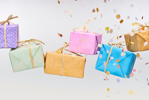 falling colorful confetti near wrapped presents on white - Фото, изображение