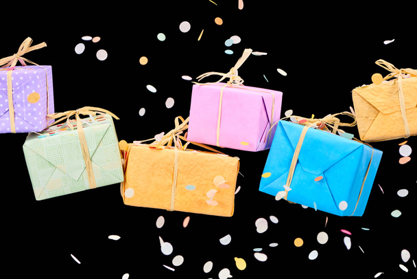 falling confetti near colorful gift boxes on black - Foto, immagini