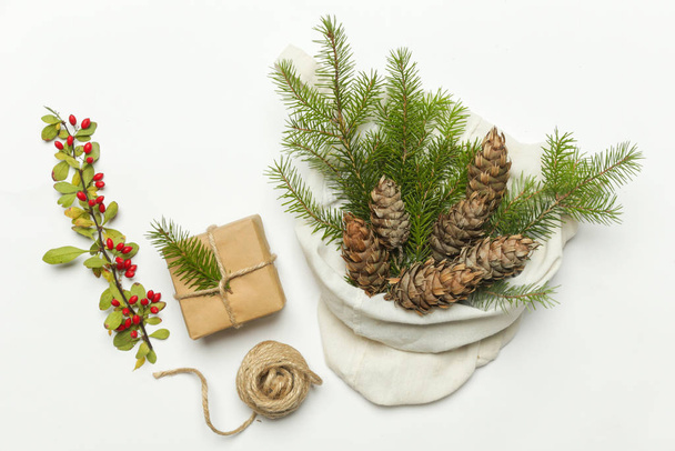 Zero Waste Verpackung Geschenke Konzept. Natürliche Weihnachtsdekoration, Tannenzapfen und Tannenzweige in Baumwolltasche. - Foto, Bild