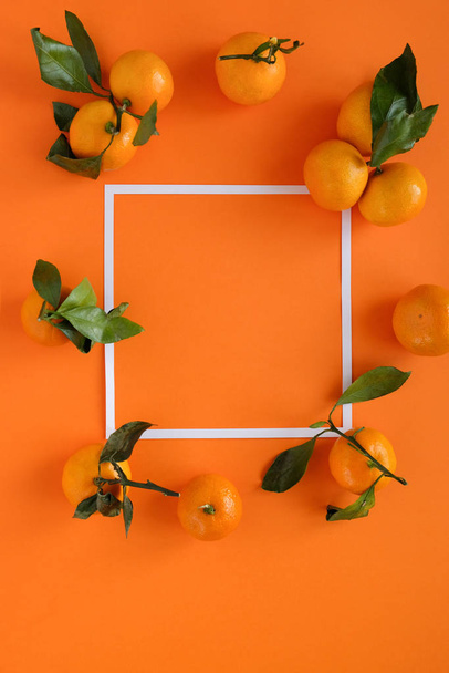 Orange tangerine with leaves on an orange background - Valokuva, kuva