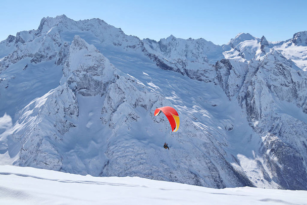 paraplano voando sobre montanhas nevadas do Cáucaso céu azul ensolarado
 - Foto, Imagem