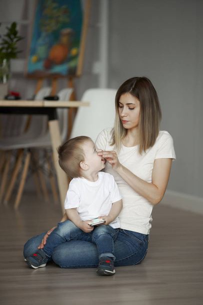 Mom and little son sitting on floor in apartment - Photo, image