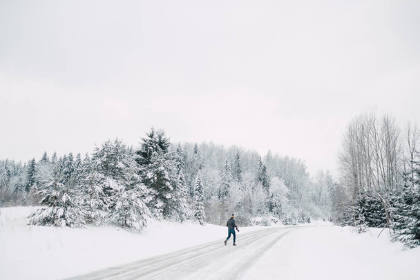 man wandelen in dennenbos tijdens het winterseizoen - Foto, afbeelding
