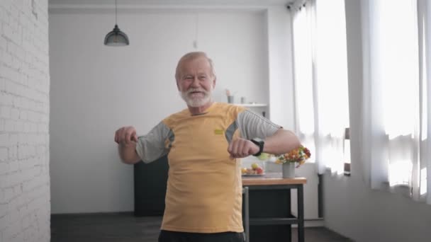 hyvinvointi harjoitukset, iäkäs mies huolehtii terveydestä suorittaa harjoituksia heiluttaen aseita seistessä sisätiloissa
 - Materiaali, video