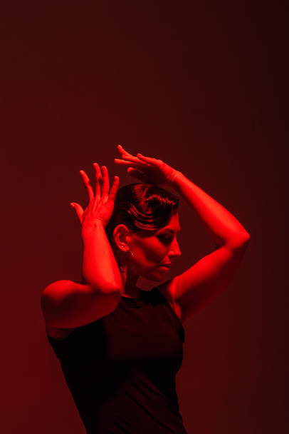 expressive dancer performing tango on dark background with red lighting - Φωτογραφία, εικόνα