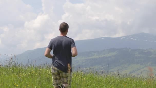 Fiatal ember turista felemeli a kezét a győztes gestion, miközben túrázik a nyári hegyekben. - Felvétel, videó