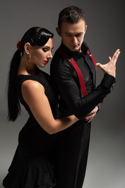 beautiful dancer embracing partner while performing tango on grey background - Photo, Image