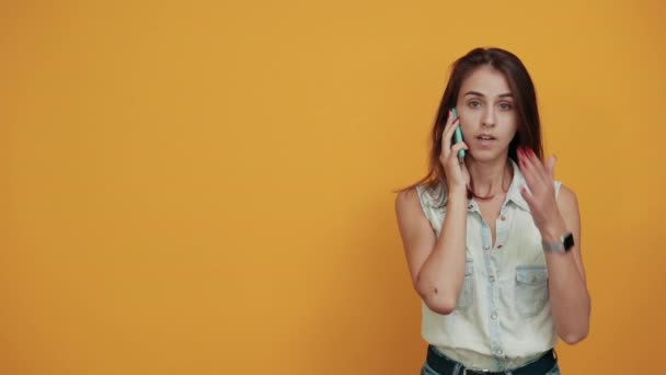Woman keeping hand on mouth, holding telephone, speaking about something - Materiał filmowy, wideo