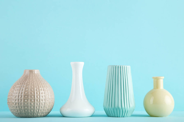 Different ceramic vases on blue background - Фото, изображение