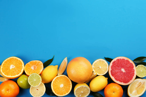 Flat lay composition with tangerines and different citrus fruits on blue background. Space for text - Fotografie, Obrázek