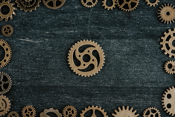 top view of vintage metal gears arranged in frame on dark wooden background - 写真・画像