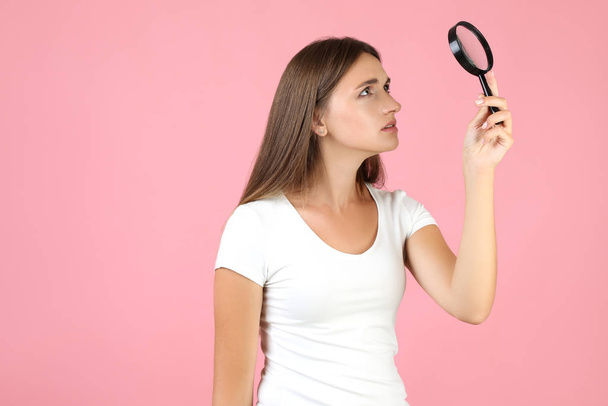 Young woman with magnifying glass on pink background - Photo, image