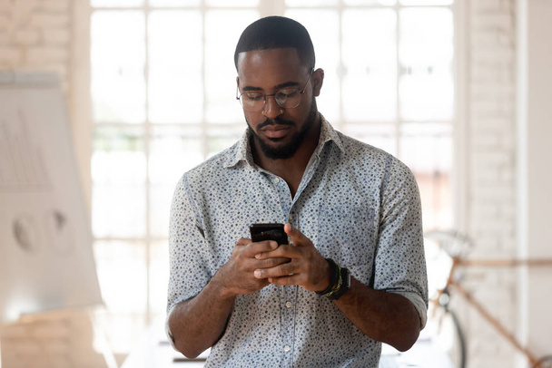 Serious african american young employee using smartphone. - Photo, Image