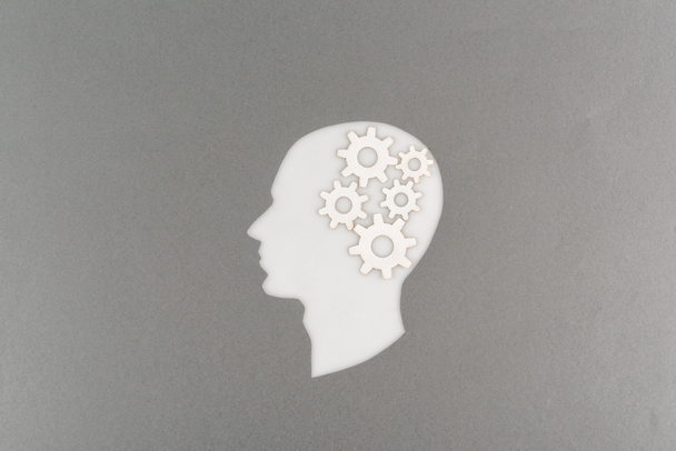 top view of cut out white human head with gears isolated on grey - 写真・画像