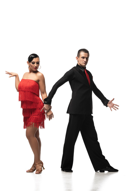 sensual, elegant dancer looking at camera and holding hand of attractive partner while performing tango on white background - Photo, Image