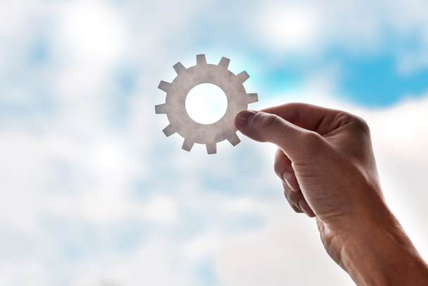 cropped view of man holding gears on blue sky background - Photo, Image