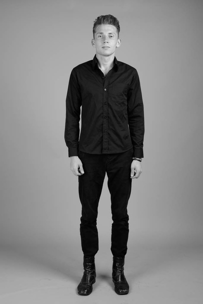 Studio záběr mladého podnikatele proti šedé pozadí v černé a bílé - Fotografie, Obrázek