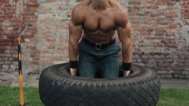 Handsome young man holding a tire and doing squats - Footage, Video